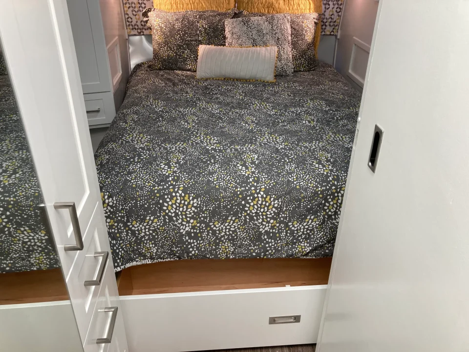 Open storage drawer beneath the bed in the renovated Airstream bedroom.