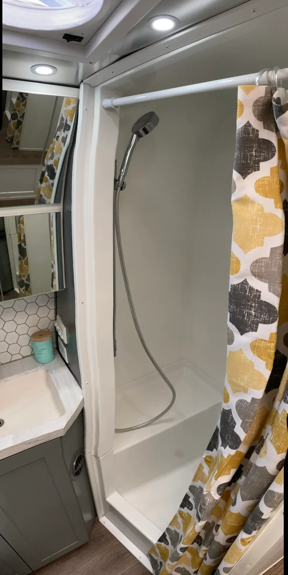 Compact white shower with a handheld showerhead beside the Airstream bathroom vanity.