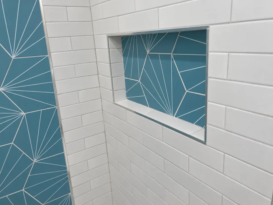 Blue-tiled shower niche set into white subway tile