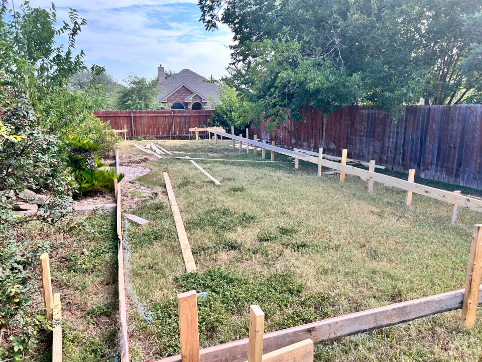 Detached ADU footprint marked out with timber boards and stakes on the lawn before excavation