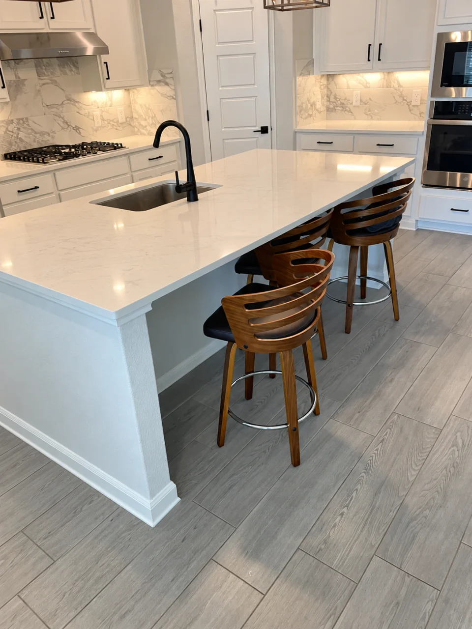 Before the refresh: a plain painted kitchen island with a white countertop, black faucet and wood bar stools.
