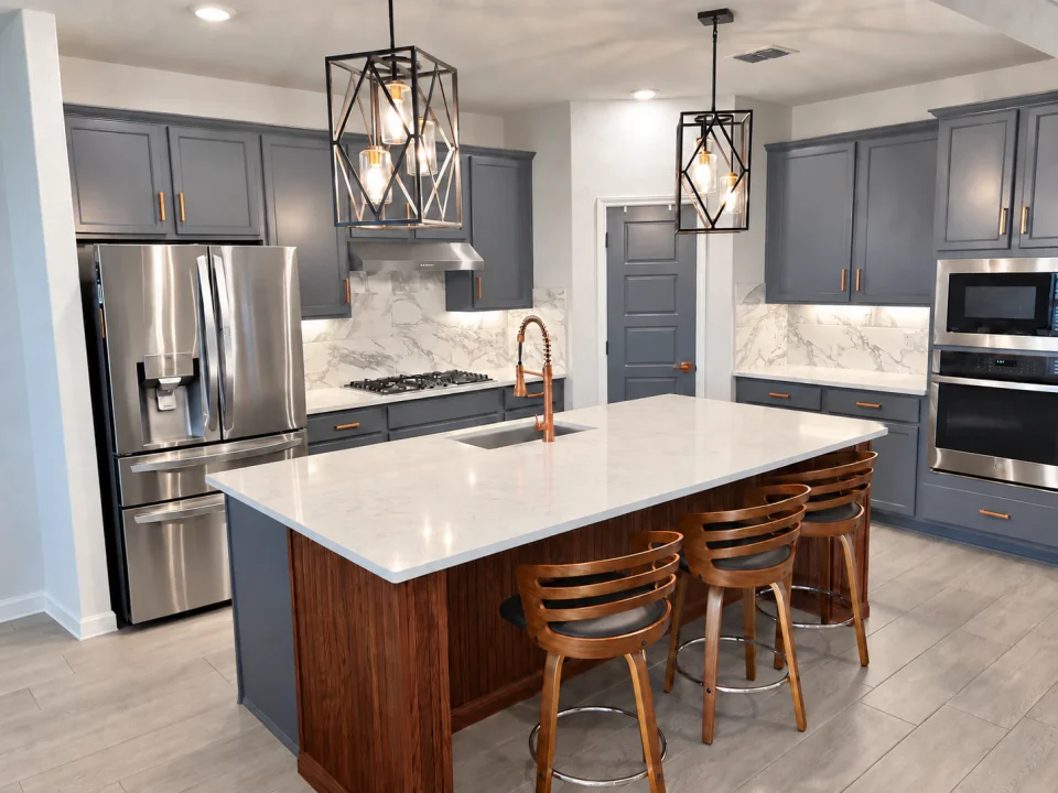 Refinished gray kitchen cabinets with a wood island, white countertop, copper-toned faucet and geometric pendant lights