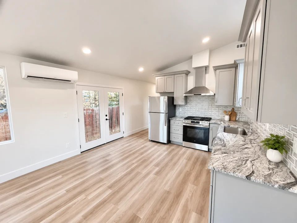 Bright detached ADU kitchen with light gray cabinets, patterned counters and French doors