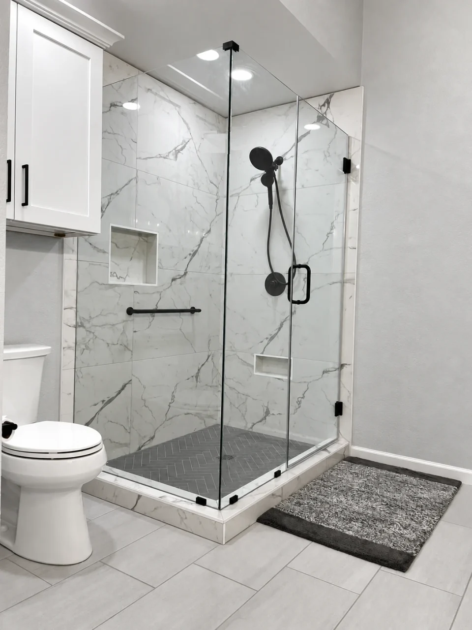 Glass-enclosed shower with large marble-look tile