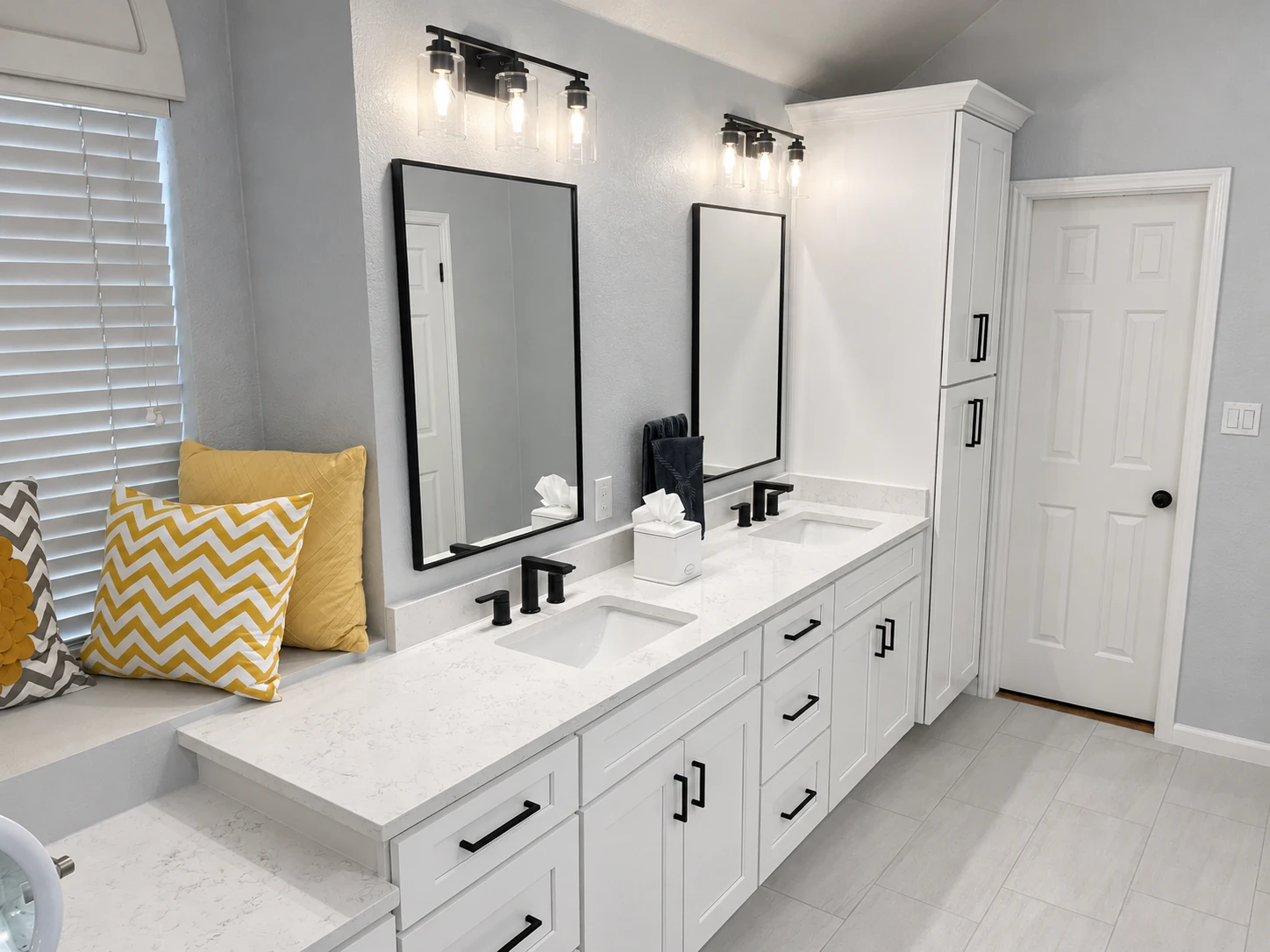 White bathroom vanity with black handles and two mirrors