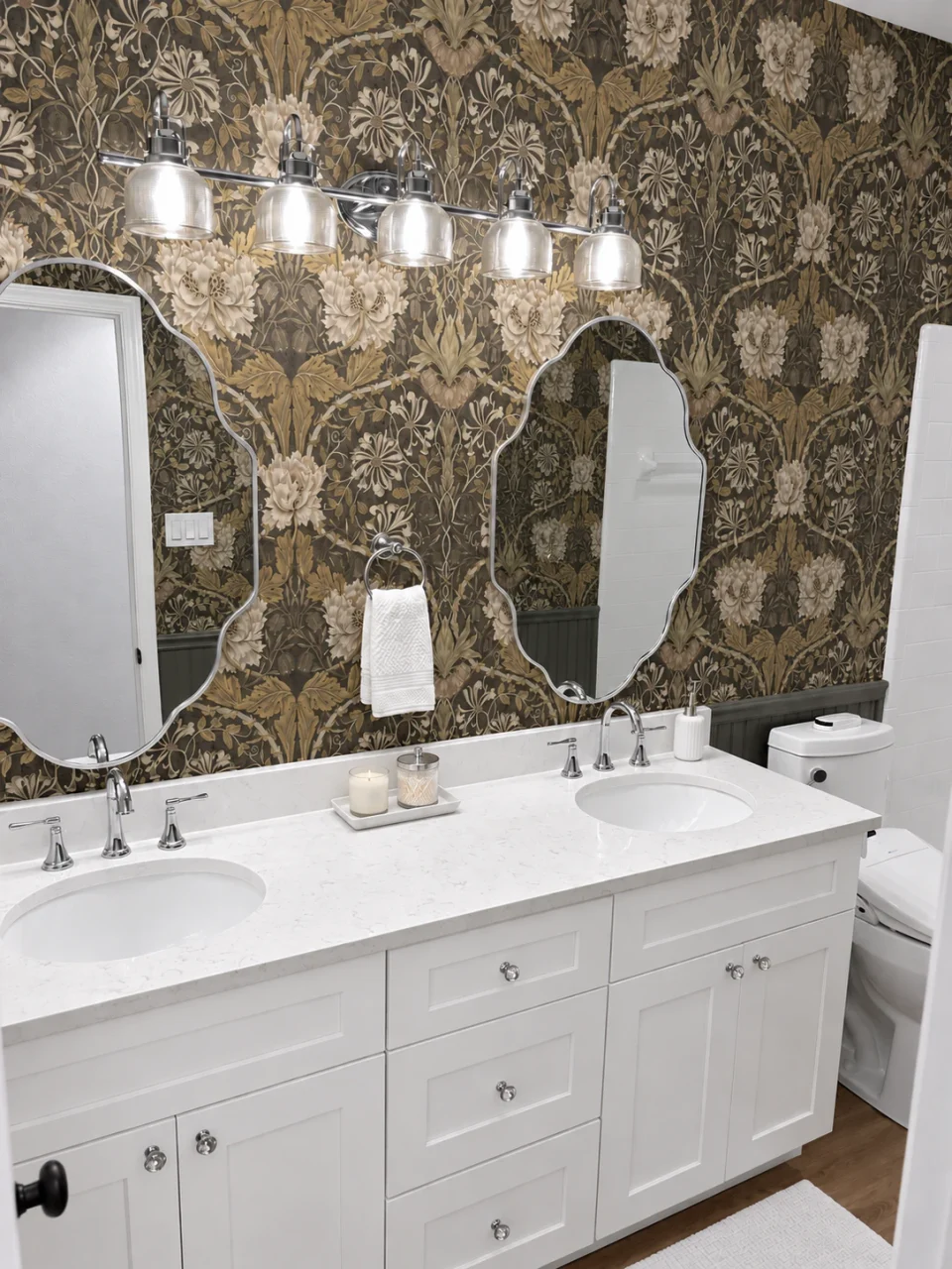 Bright white double vanity with gray-veined white counters, shaped mirrors and Morris & Co botanical wallpaper.