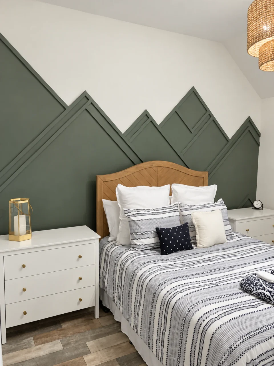 Angled view of the olive-green mountain wall trim behind the wood bed and white nightstands