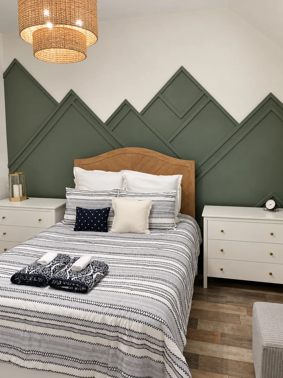 Finished bedroom with an olive-green mountain feature wall, wood headboard and woven pendant