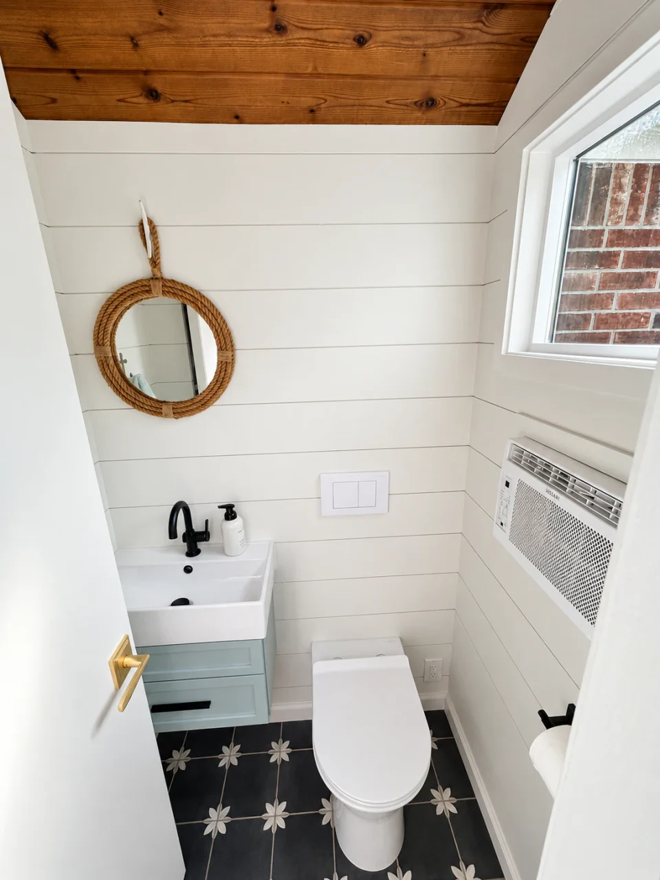 Outdoor pool bathroom with white shiplap, a pale blue vanity, patterned floor tile and wood ceiling