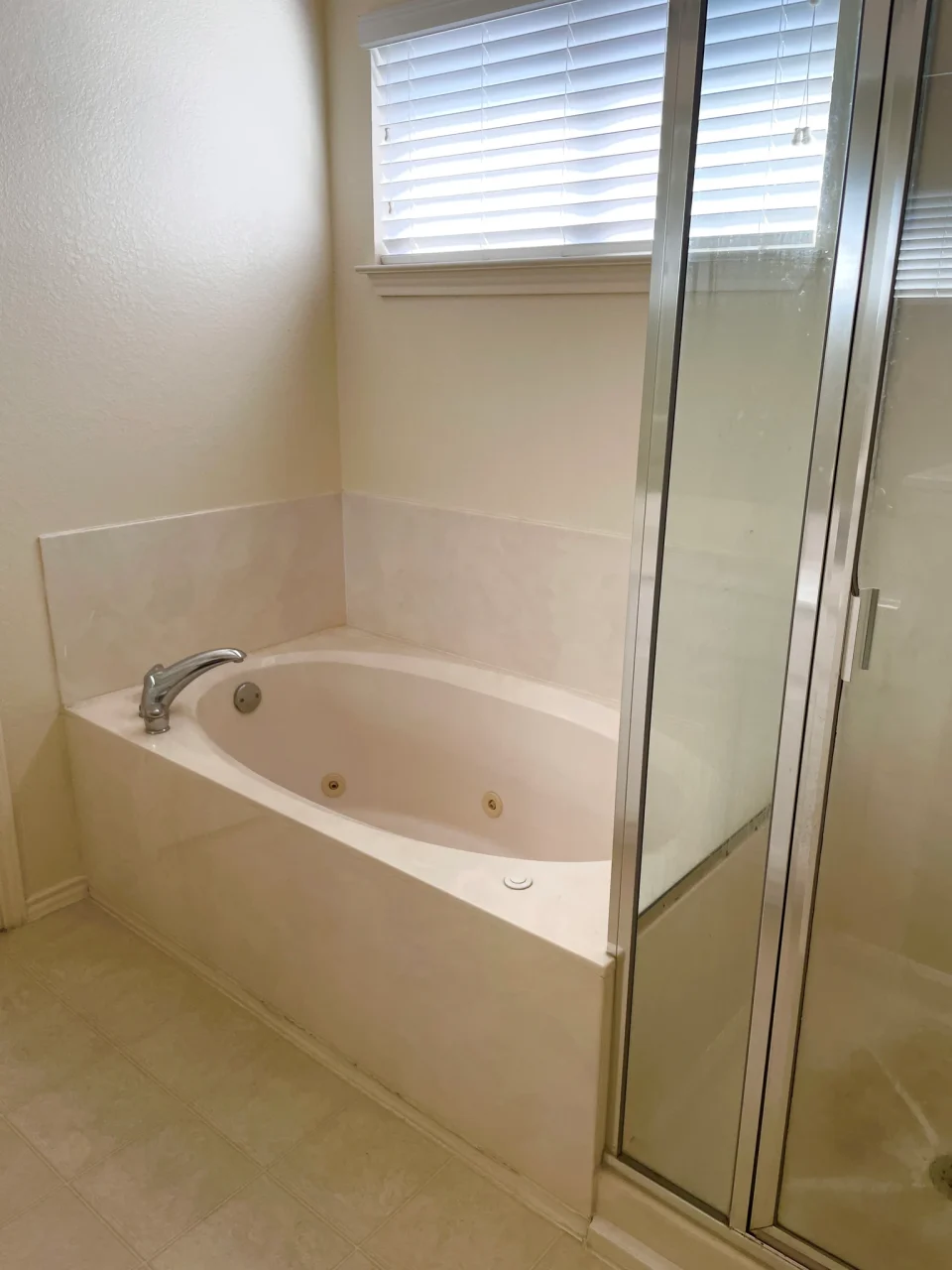 Original bathroom with a beige bathtub and a separate framed shower enclosure before renovation.