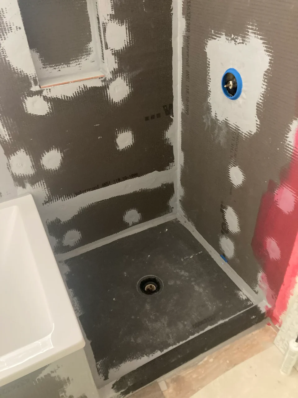 Shower pan and sealed wall boards during waterproofing, before the tile installation.