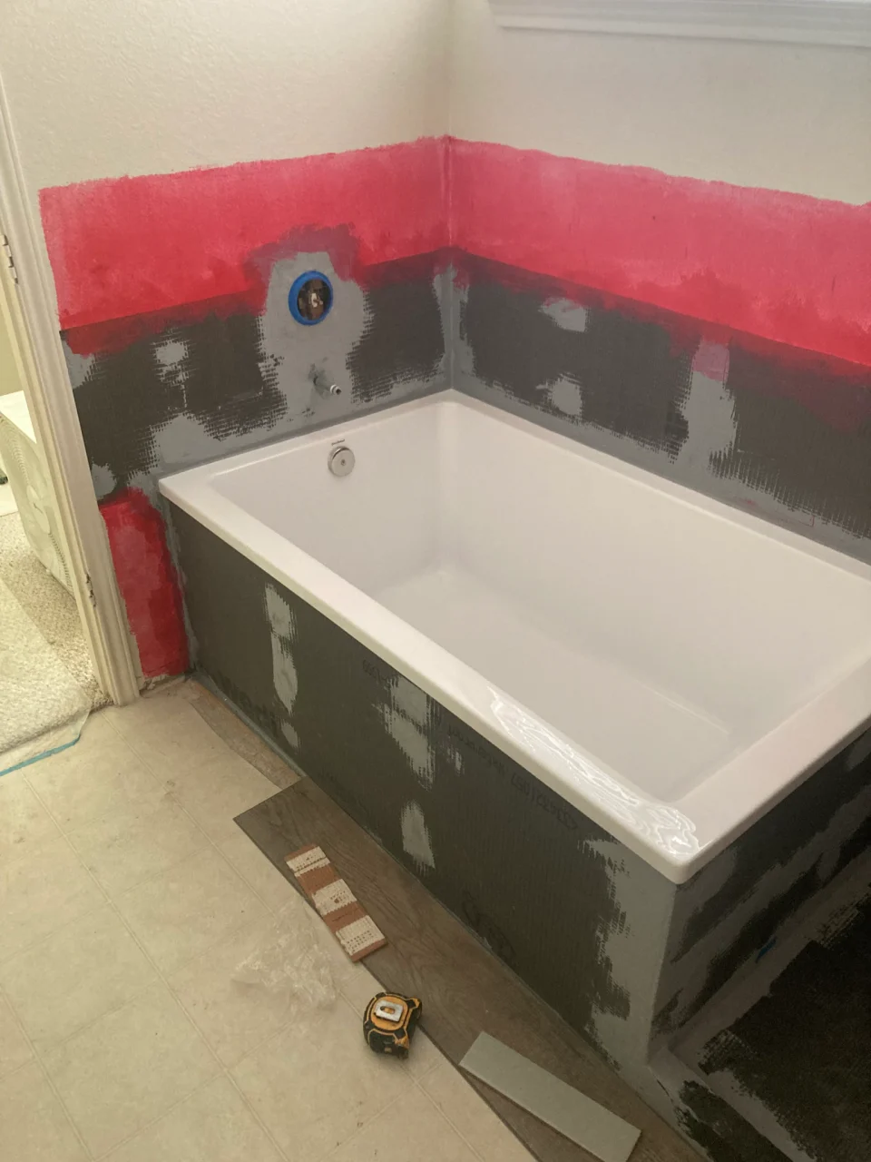 Waterproofing around the bathtub before the patterned wall tile and sage subway tile were installed.