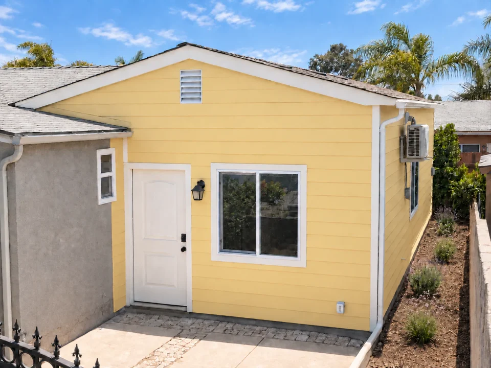 Yellow attached ADU with sliding door and small entry patio