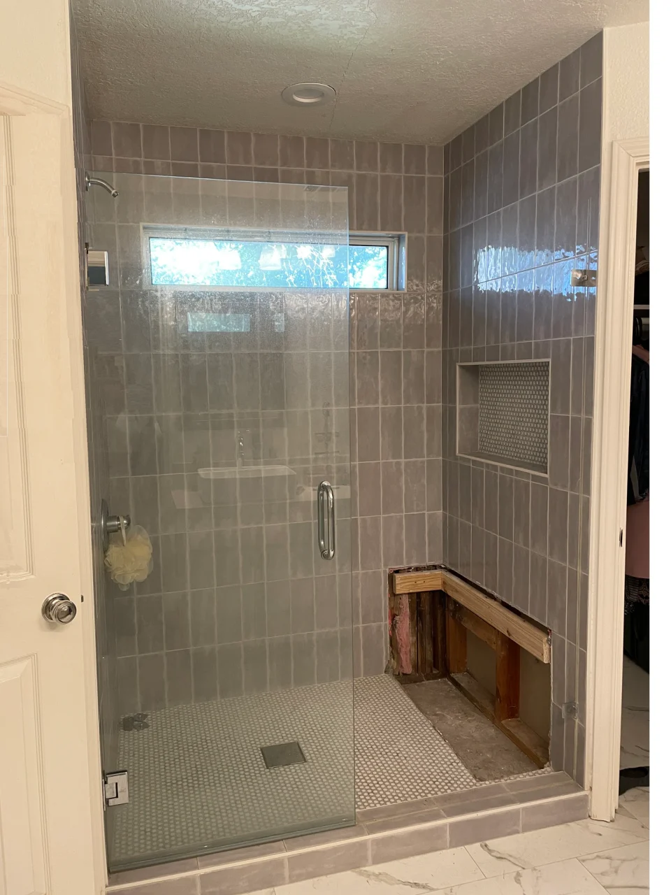 Original shower with tan tile, a framed glass door and a wooden seat