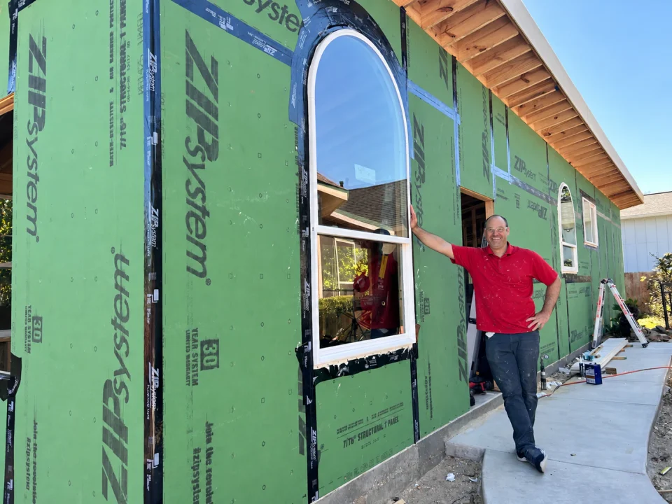 Jake beside the arched ADU window during construction