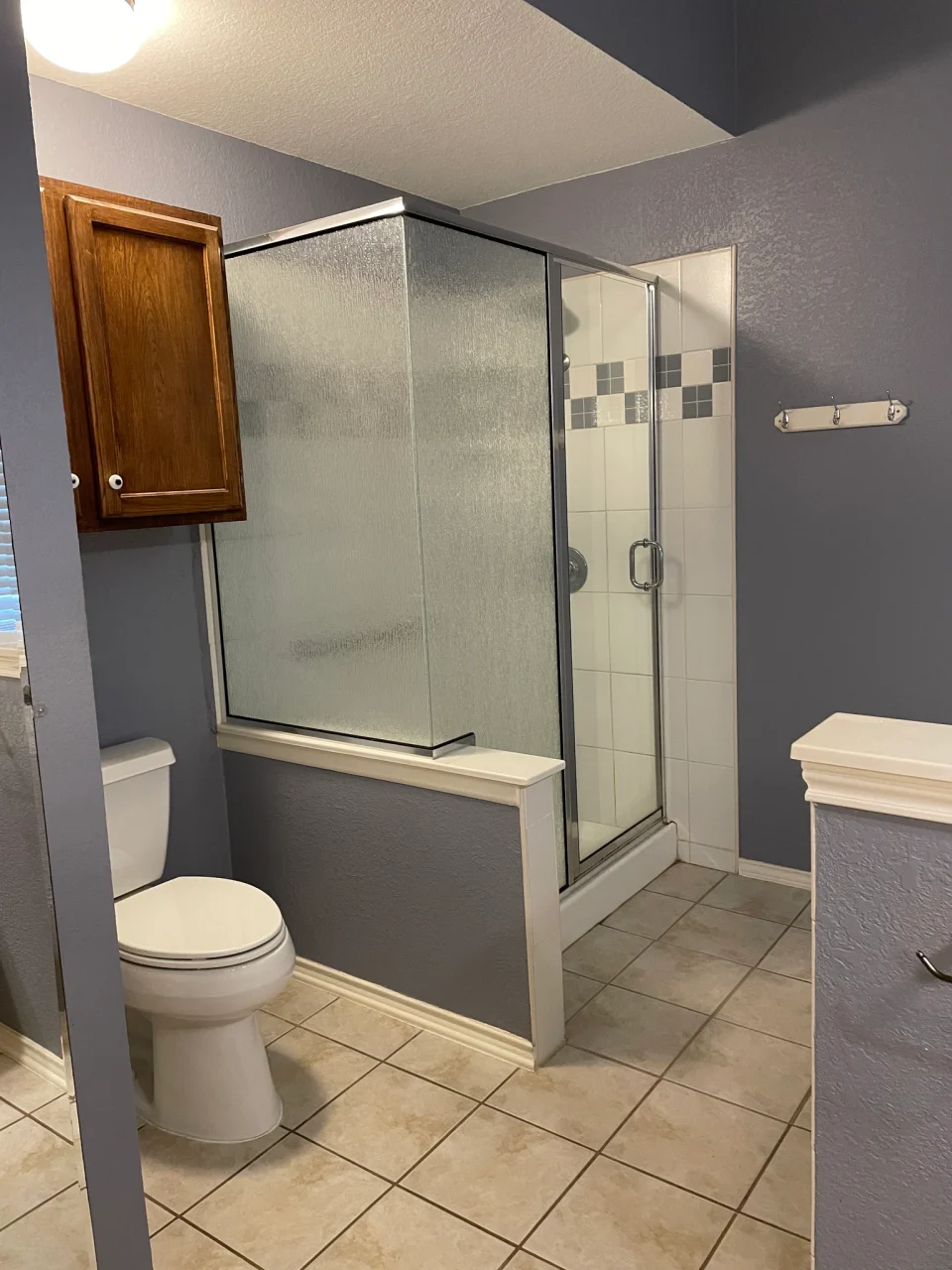 Before renovation: shower beside wood vanity cabinetry