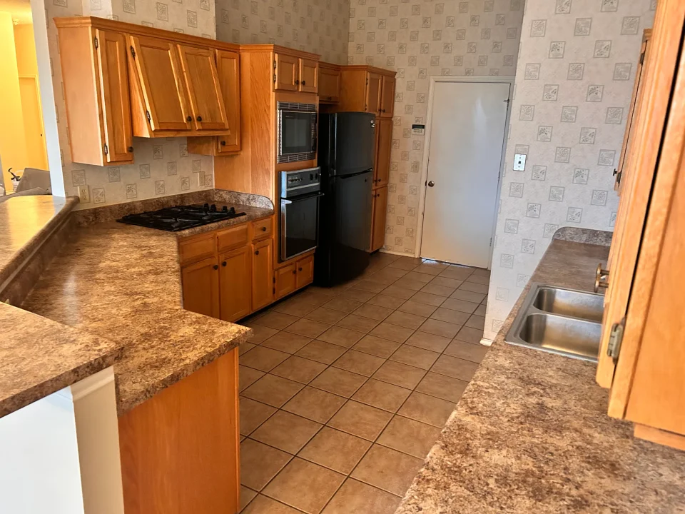 Before renovation: wood kitchen cabinetry and tiled floor