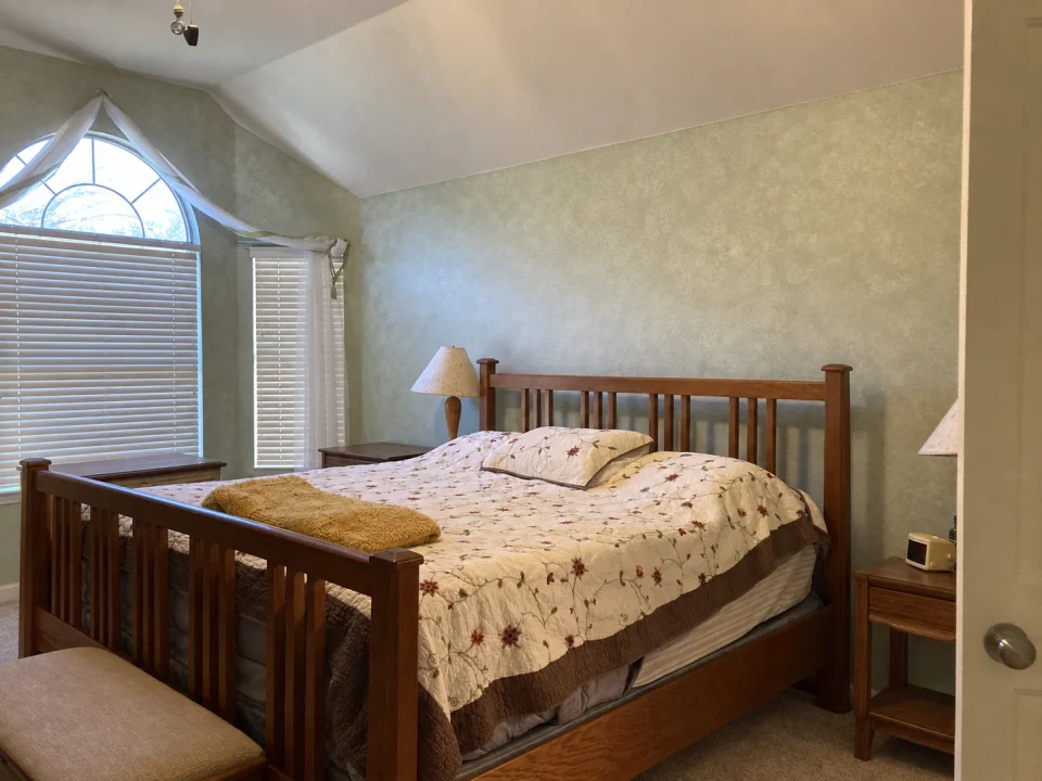 Before renovation: vaulted bedroom with a wood bed and pale walls