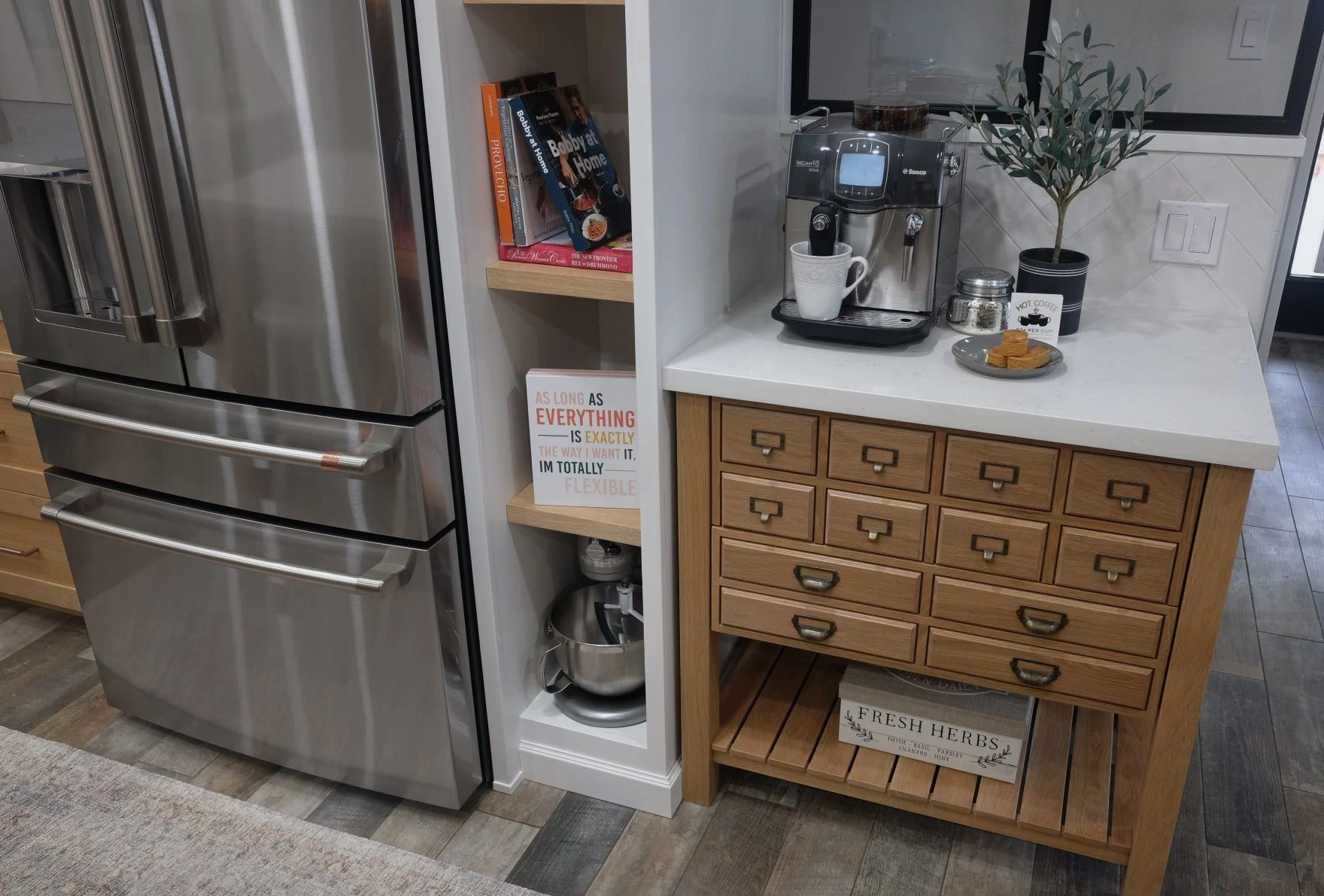 Coffee station and oak apothecary cabinet beside a stainless steel refrigerator