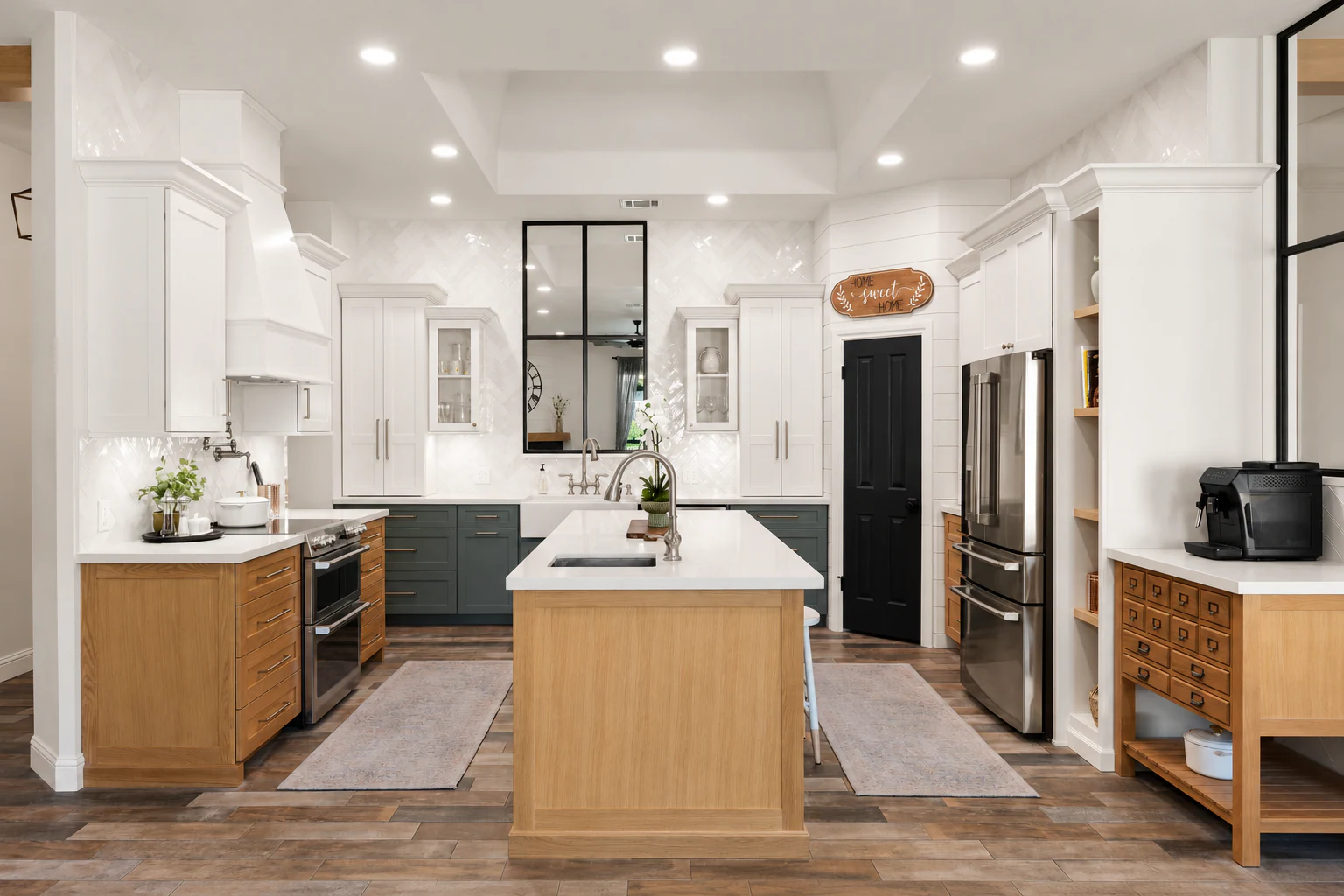 Custom kitchen from a whole-home renovation with a large island, white cabinetry, warm white oak, green accents, and a custom apothecary cabinet