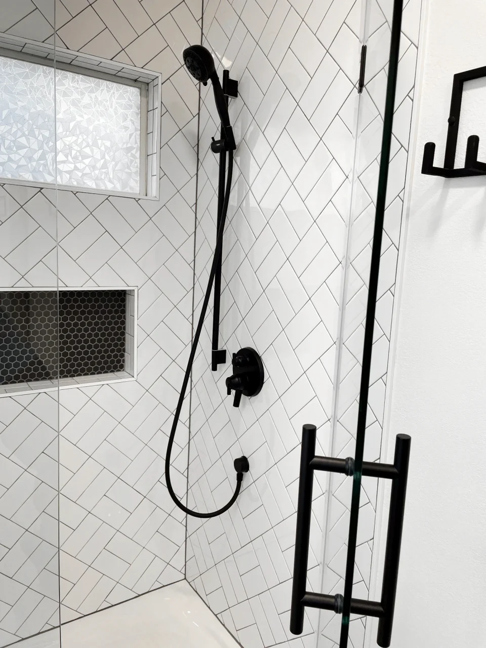 Black shower fixtures against basket-weave tile