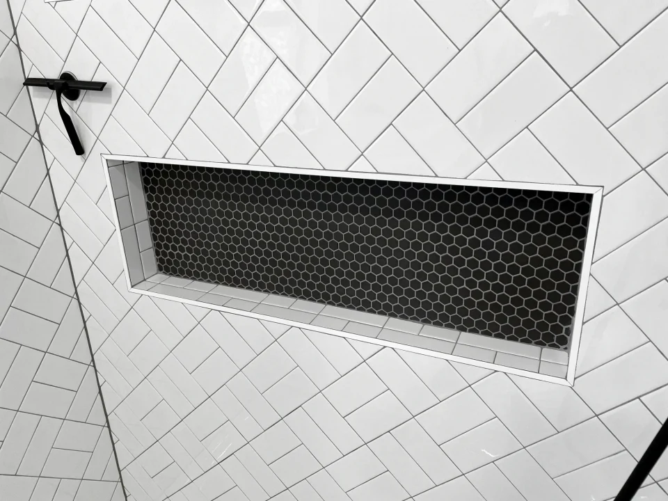 Dark recessed niche surrounded by white basket-weave tile
