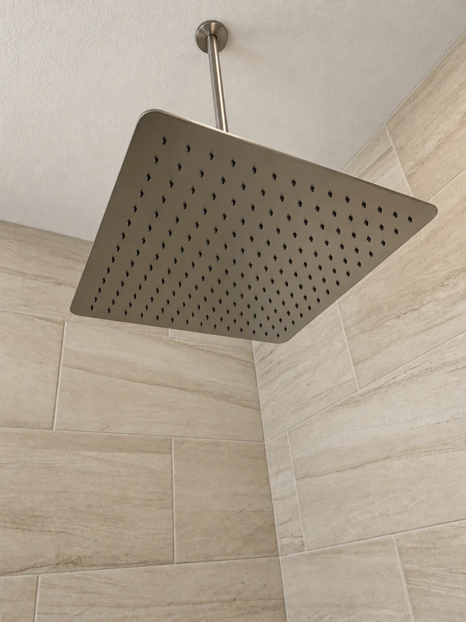 Square rain shower head against warm-toned tile