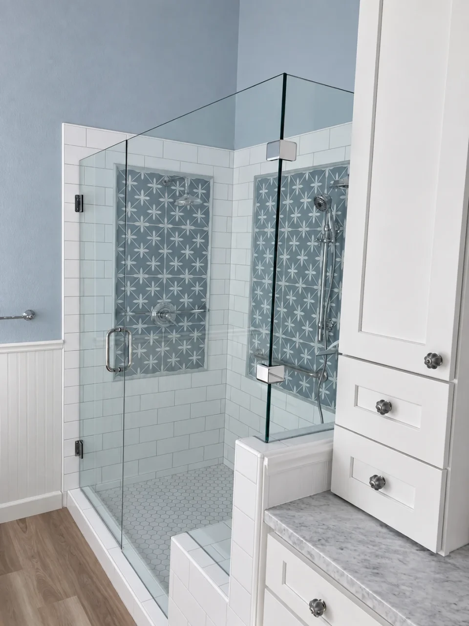 Glass shower beside traditional white vanity cabinetry