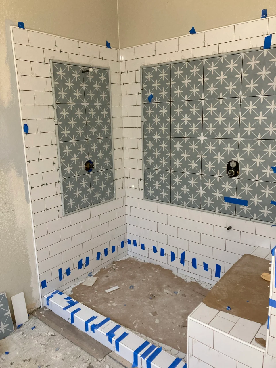 White subway tile and blue-gray star-patterned shower panels during installation