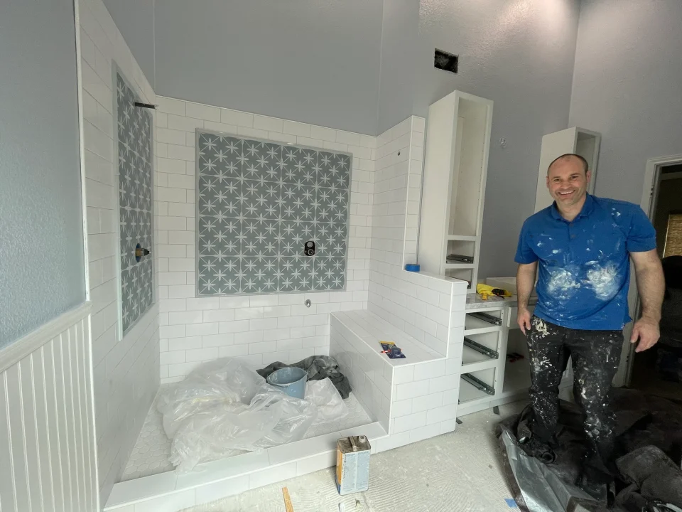 Jake working beside the new patterned-tile shower before the glass is installed