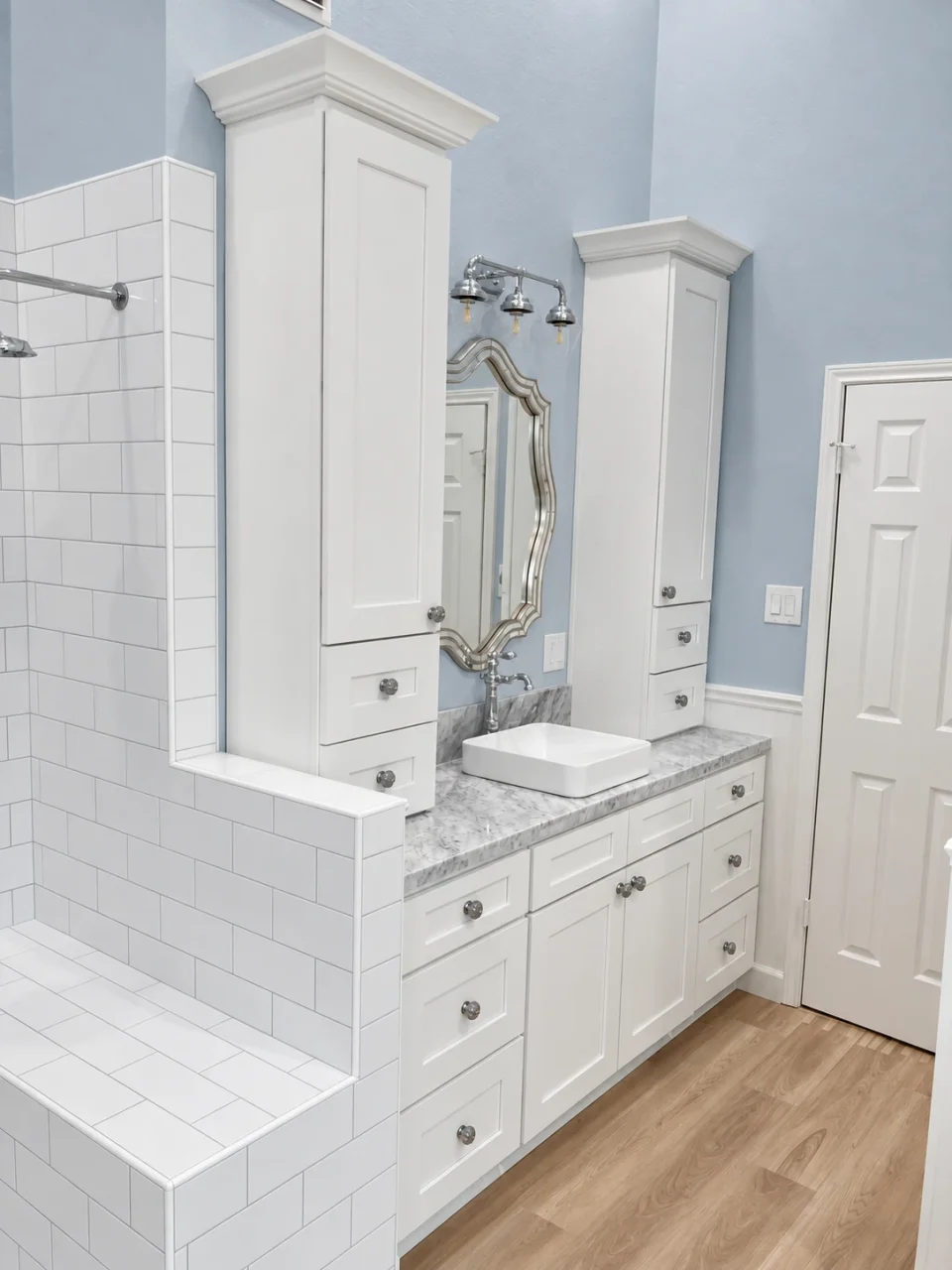 White bathroom cabinetry and decorative framed mirror