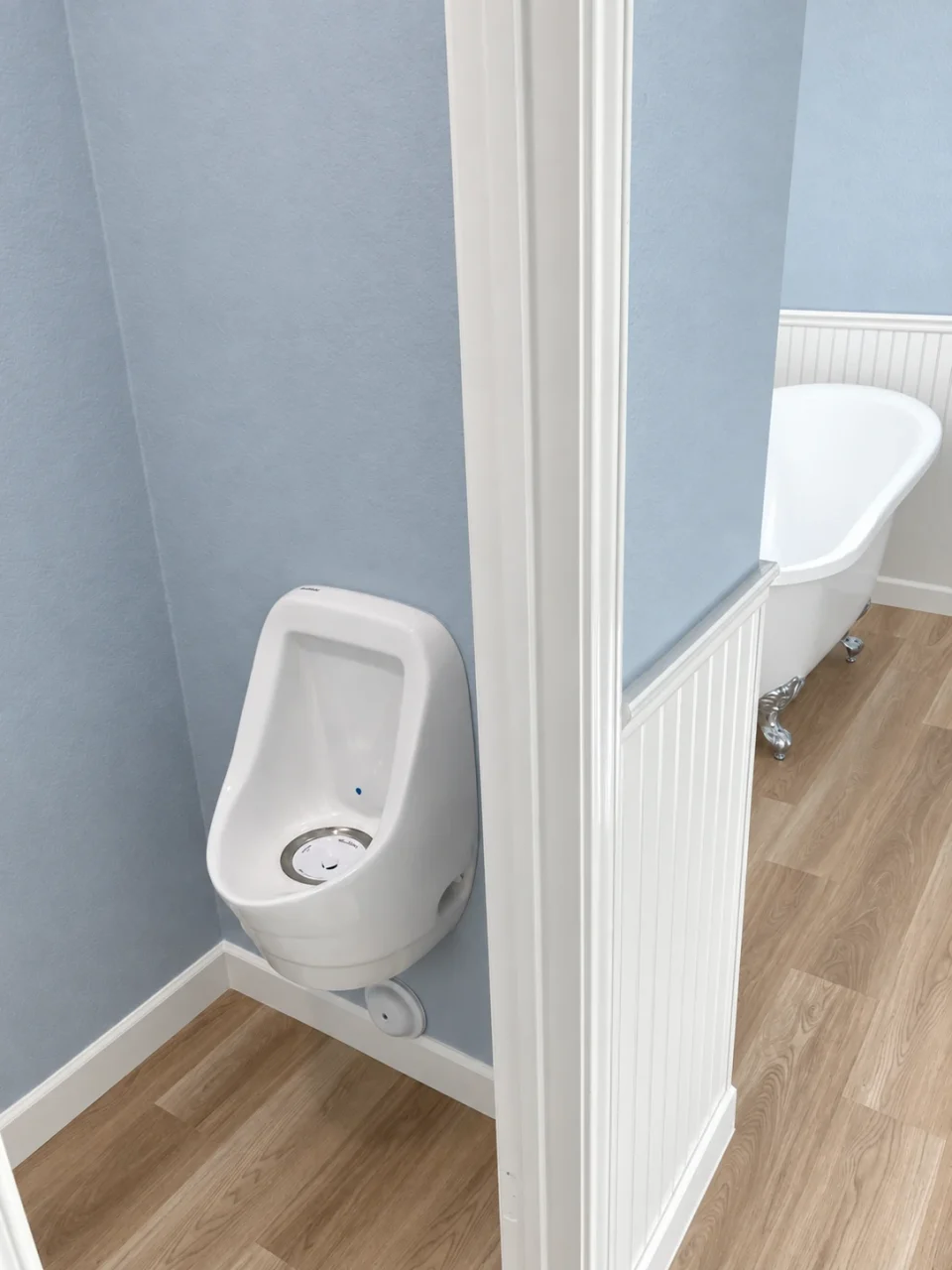 White wall-mounted urinal in a separate alcove beside the primary bathroom