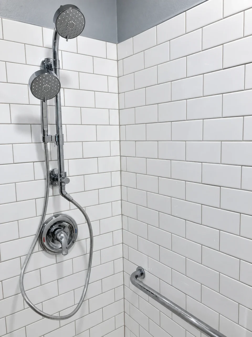 Handheld shower on a rail against white subway tile