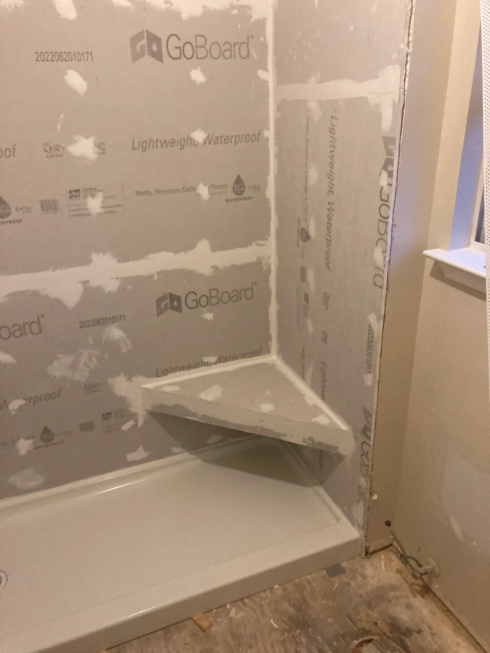 In progress: corner shower bench and sealed wall panels before tile