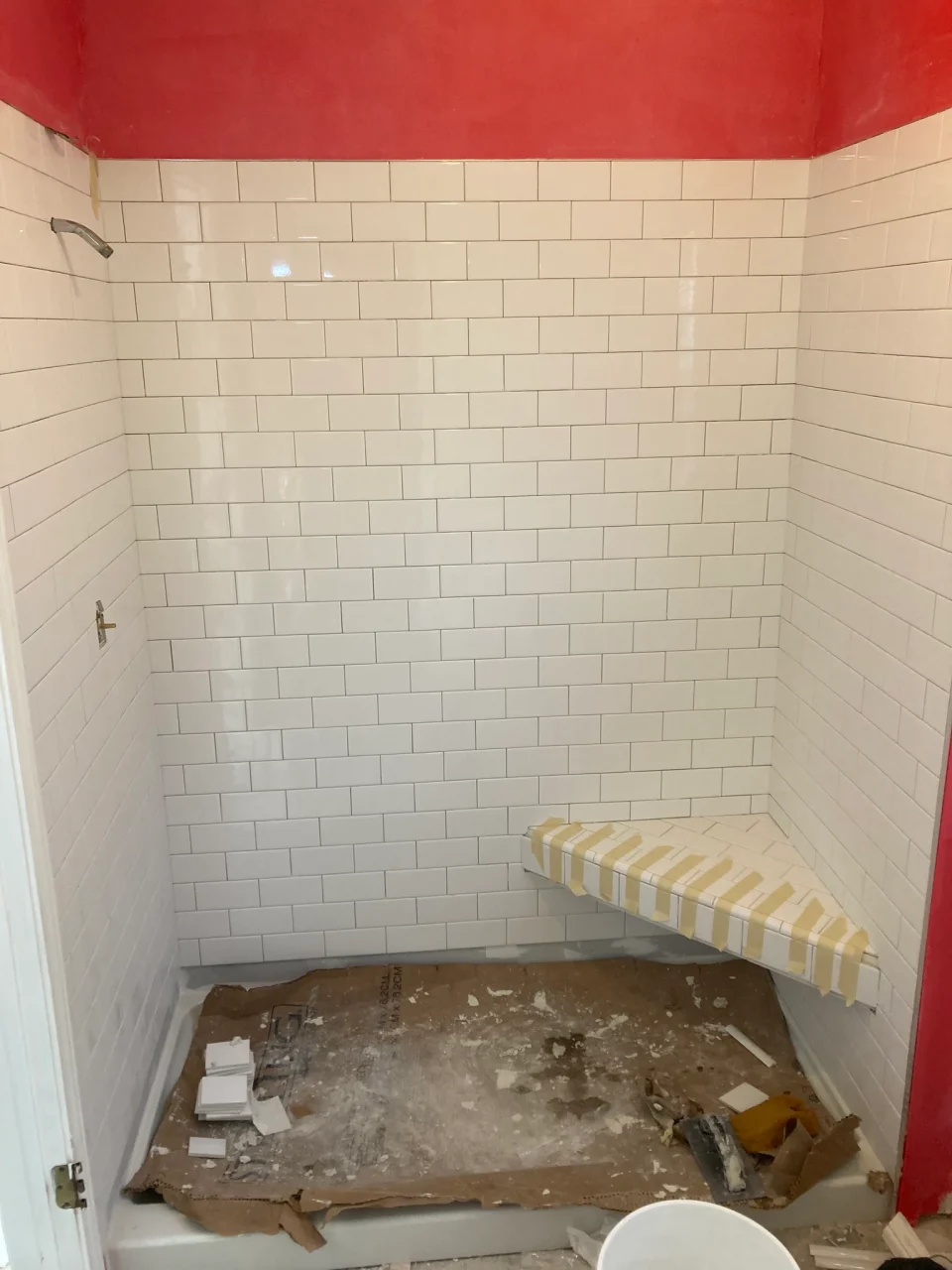 In progress: white subway tile walls and corner bench during installation