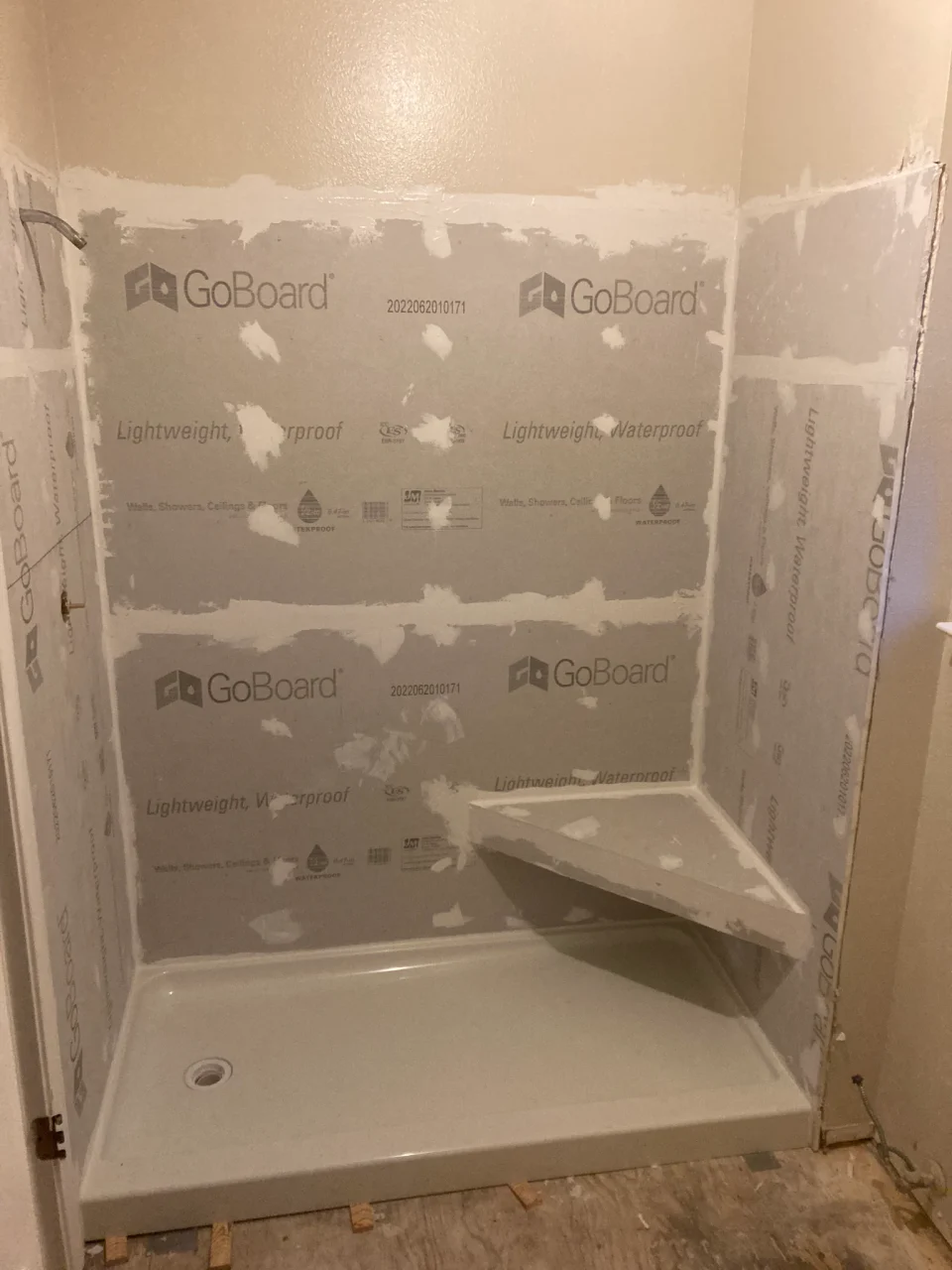 In progress: sealed shower wall panels, shower base and corner bench before tiling