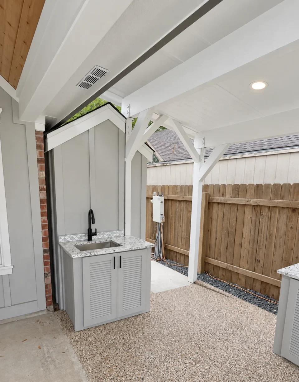 Custom outdoor kitchen sink station with a freestanding outdoor powder room behind it beneath the covered patio.